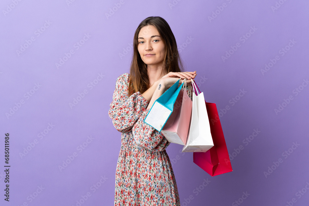 Young Ireland woman isolated on purple background holding shopping bags