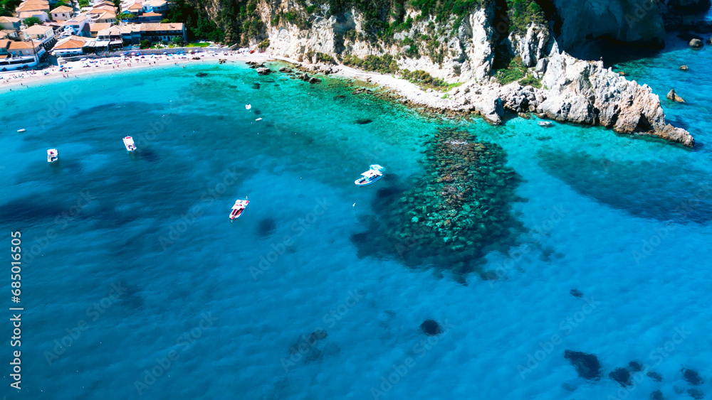 Aerial view of little boats floating in turquoise crystal clear transparent sea water by cliffs 