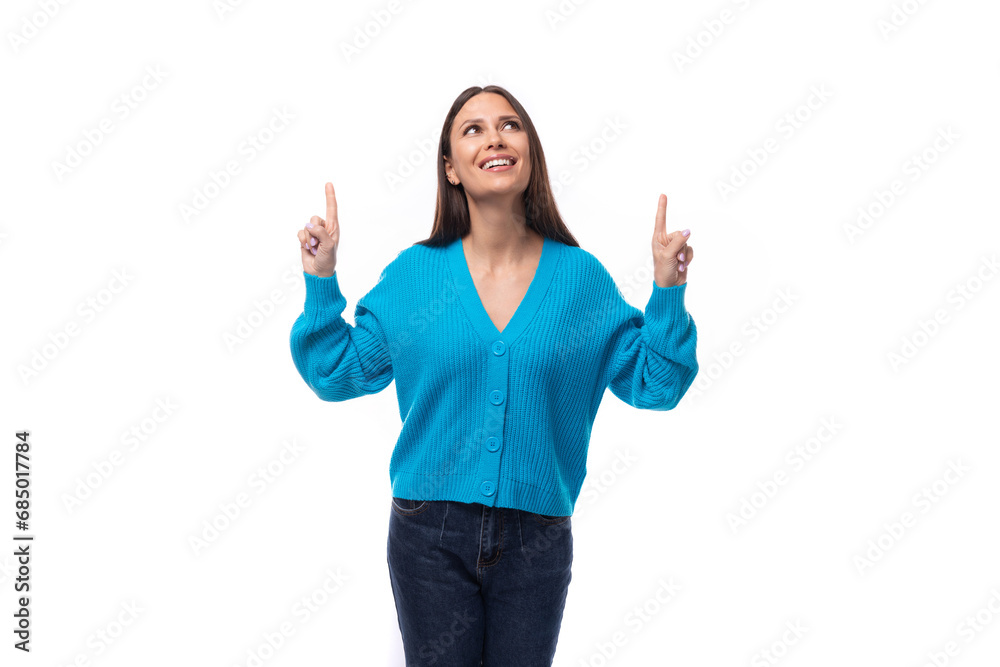 young stylish brunette promoter lady dressed in a blue V-neck sweater shows her hand to the advertising space on a white background with copy space young stylish brunette promoter lady dressed in a blue V-neck sweater shows her hand to the advertising space on a white background with copy space