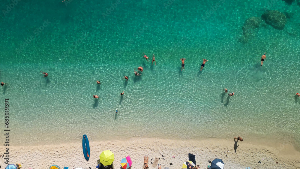 Aerial view of people sunbathing and swimming in turquoise crystal clear sea water Aerial view of people sunbathing and swimming in turquoise crystal clear sea water