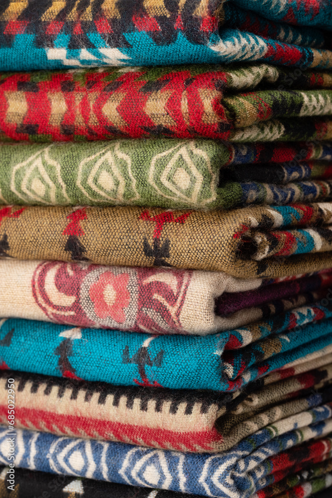 Warm rugs, stoles are stacked in stack of several rows. Accessories for cold weather from natural material. Warm rugs, stoles are stacked in stack of several rows. Accessories for cold weather from natural material.