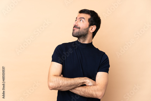 Caucasian handsome man over isolated background looking up while smiling