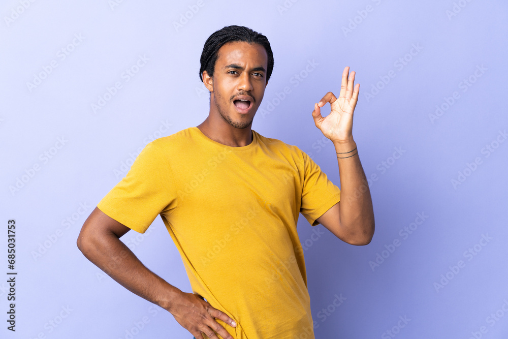 Young African American man with braids man isolated on purple background showing ok sign with fingers Young African American man with braids man isolated on purple background showing ok sign with fingers