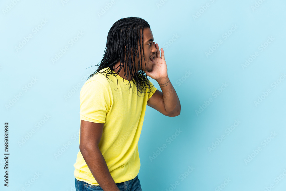 Delivery African American man with braids isolated on white background shouting with mouth wide open to the side