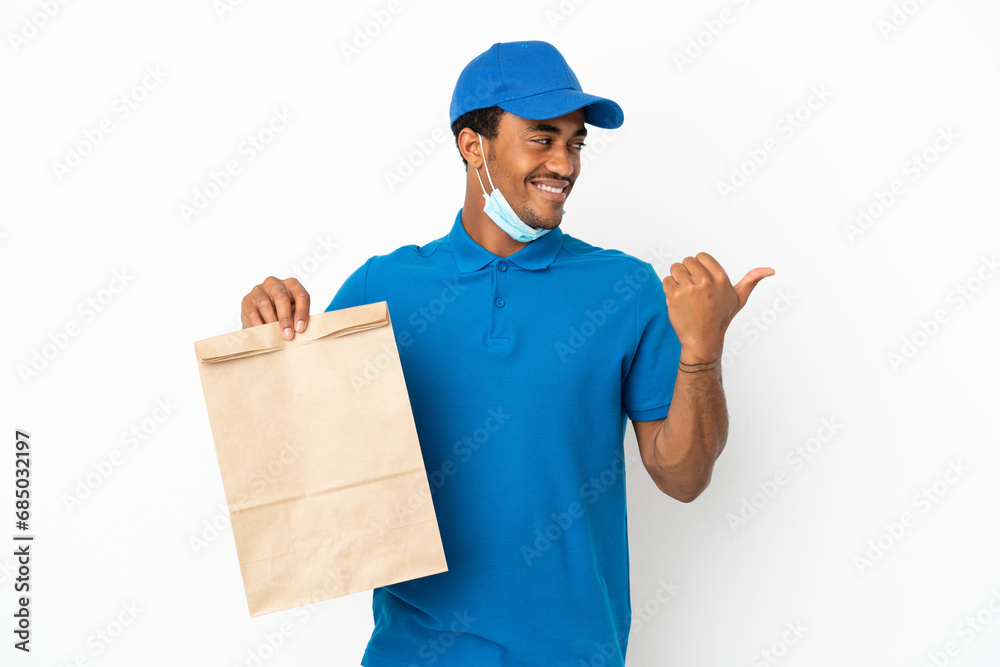 African American man taking a bag of takeaway food isolated on white background pointing to the side to present a product African American man taking a bag of takeaway food isolated on white background pointing to the side to present a product