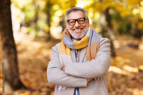 Portrait of happy positive mature man with broad smile    in elegant clothes on an autumn walk   in city park photo