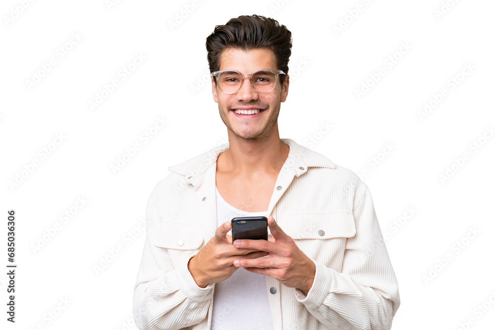 Young handsome caucasian man over isolated background sending a message with the mobile Young handsome caucasian man over isolated background sending a message with the mobile