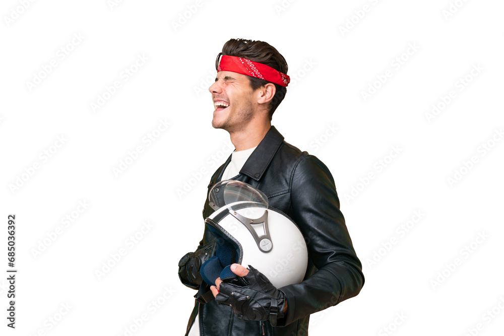Young caucasian man with a motorcycle helmet over isolated background laughing in lateral position Young caucasian man with a motorcycle helmet over isolated background laughing in lateral position