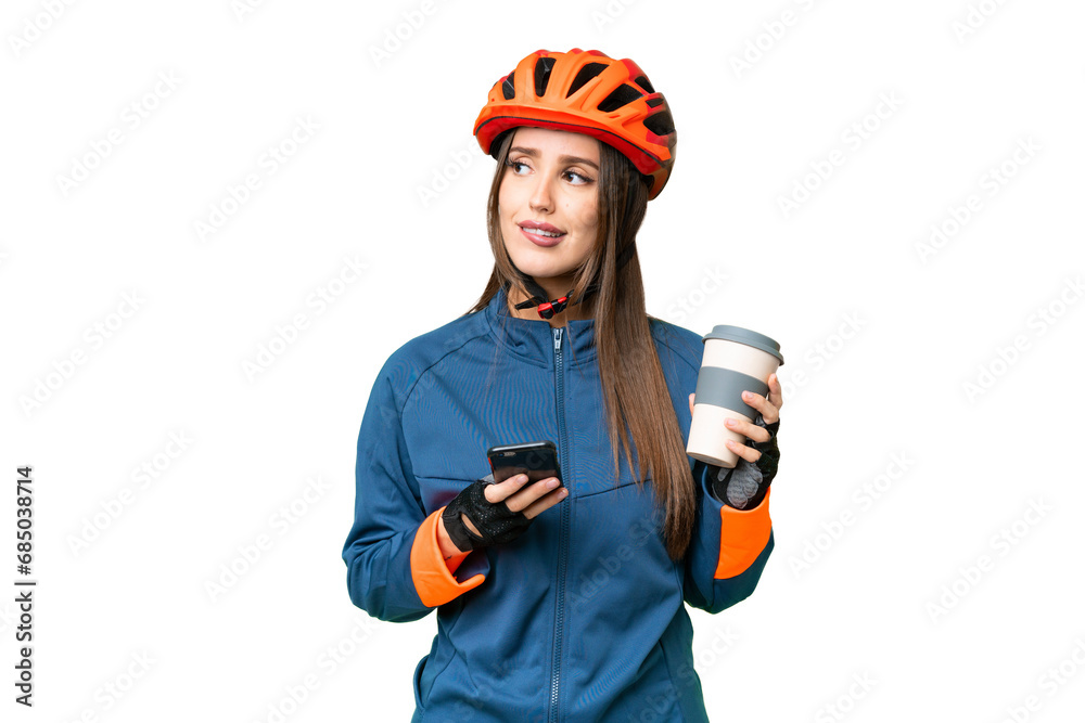 Young cyclist woman over isolated chroma key background holding coffee to take away and a mobile while thinking something