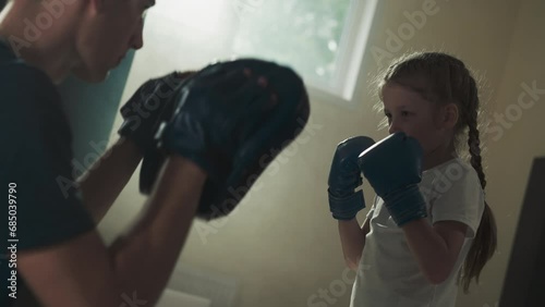 Trainer with pads and punching girl child in gym photo