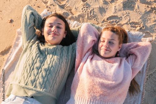Happy young girlfriends resting on sandy beach during vacation #685046317