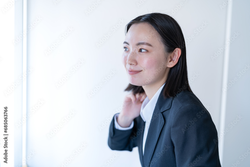 洗面所で身支度をする笑顔のスーツを着た若い女性