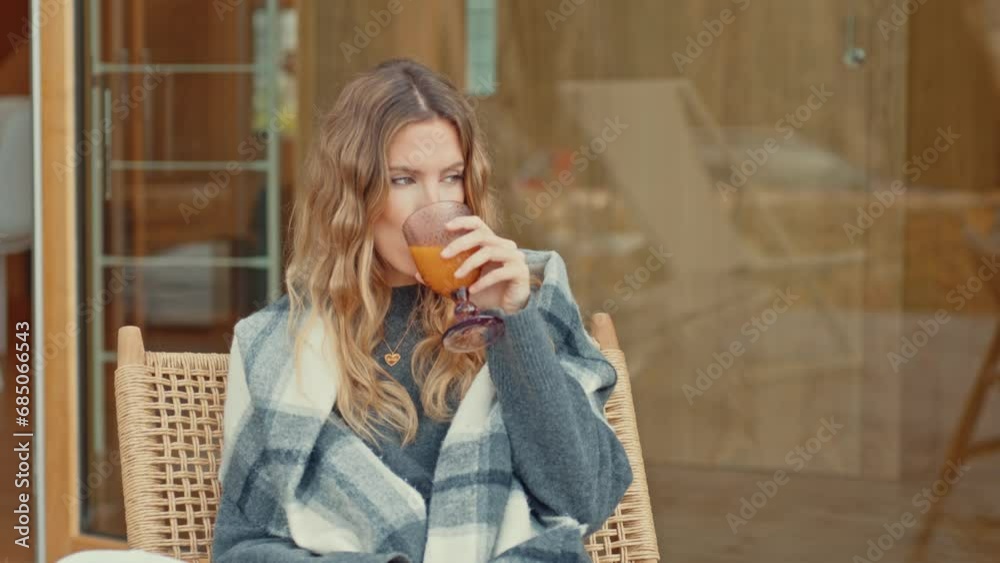 Contemplative woman sipping juice, wrapped in warmth Contemplative woman sipping juice, wrapped in warmth