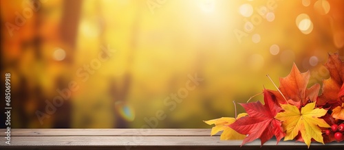 Fall themed table with red and yellow leaves amid forest backdrop copy space image