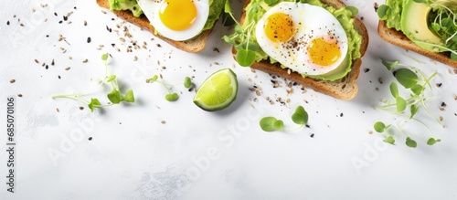 Healthy breakfast featuring avocado egg sandwiches and coffee served on a white table with whole grain toasts mashed avocado fried eggs and organic microgreens copy space image