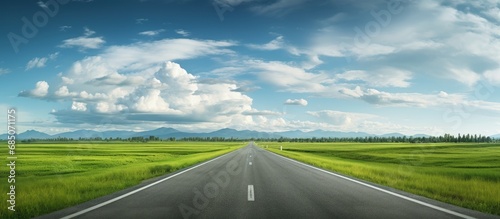 Endless road through verdant fields and sky full of clouds copy space image