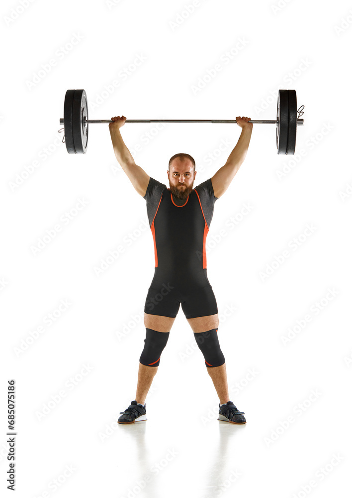 Fototapeta premium Bearded strong man, athlete training, lifting heavy weights, barbell against white background. Muscular strong body