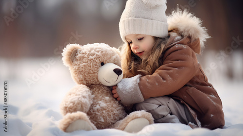 Happy cheerful little girl in winter with teddy bear on snow field. Friendship, best friend concept.