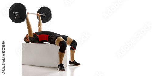 Banner. Muscular young man, athlete lying non cube and lifting heavy weight, barbell against white background photo