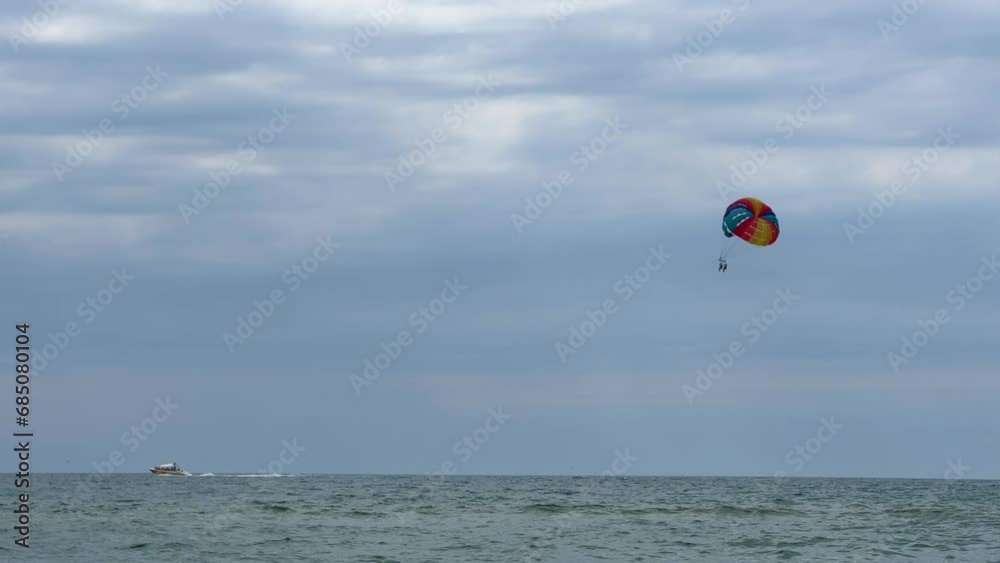 Parasailing: a boat with a marine parachute on the waves. The concept of a cloudy landscape, freedom and summer. Parachutists over the surface of the Black Sea against the sky on a summer day. 4K Parasailing: a boat with a marine parachute on the waves. The concept of a cloudy landscape, freedom and summer. Parachutists over the surface of the Black Sea against the sky on a summer day. 4K