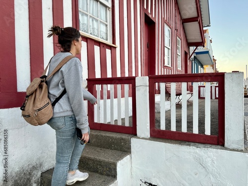 Young woman walks the streets with colorful striped houses, Costa Nova, Aveiro, Portugal