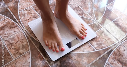 Woman measures weight on scales in morning. Overweight and measurement of body fat concept photo