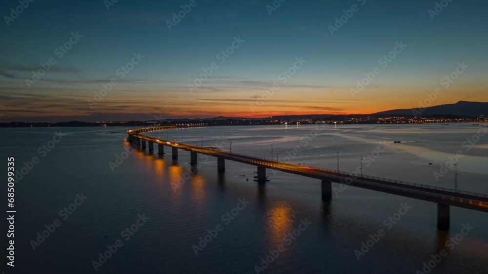 Aerial hyper-lapse view of cars driving on a long sea bridge at sunset with a beautiful golden color reflection on the surface of the sea. Concept of transportation and travel in Europe Aerial hyper-lapse view of cars driving on a long sea bridge at sunset with a beautiful golden color reflection on the surface of the sea. Concept of transportation and travel in Europe