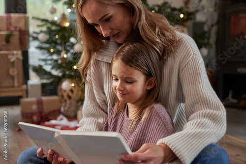 Mother and daughter reading book during Christmas time