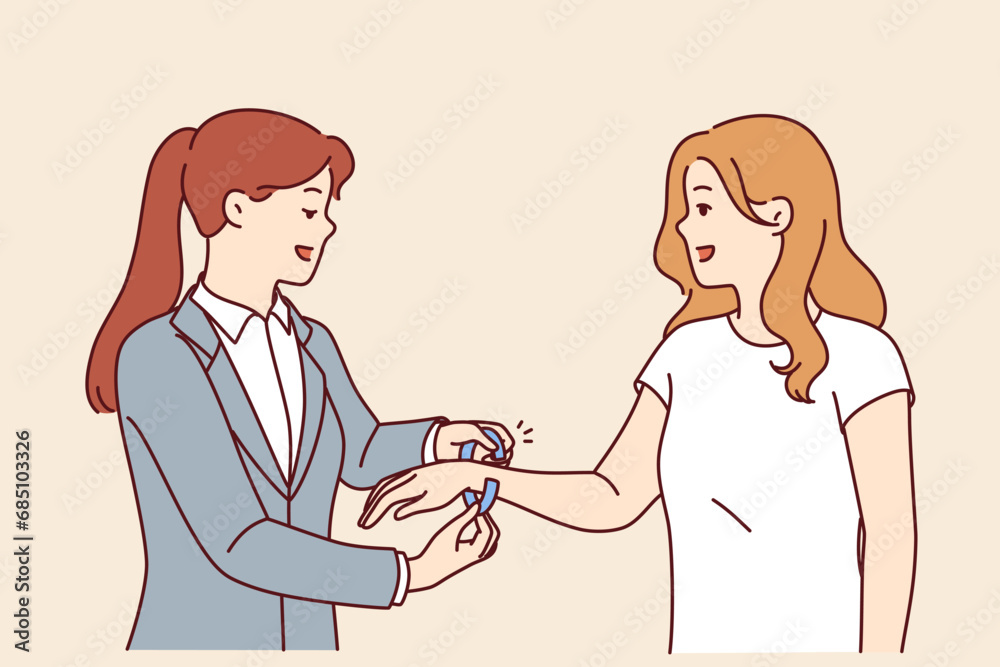 Woman administrator of nightclub puts bracelets on arm of female visitor came to closed party. Using identification bracelets to track guests of entertainment event or business forum Woman administrator of nightclub puts bracelets on arm of female visitor came to closed party. Using identification bracelets to track guests of entertainment event or business forum