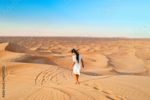 Dubai desert sand dunes, Asian woman on Dubai desert safari, United Arab Emirates vacation, woman vacation in Dubai walking in the sand dunes of Dubai