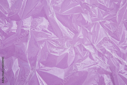 Crumpled texture of cling film on the light violet paper background