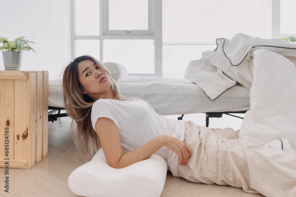 Asian Thai woman wake up from falling down from white bed, lying on floor with funny drowsy and sluggish stun face in morning time alone in apartment home. Asian Thai woman wake up from falling down from white bed, lying on floor with funny drowsy and sluggish stun face in morning time alone in apartment home.