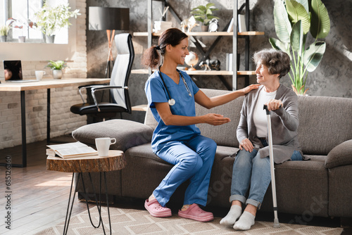 Nurse caregiver doctor giving advice to elderly senior woman, prescribing treatment at home. Hospice elderly care. Geriatrics concept. Disabled patient photo