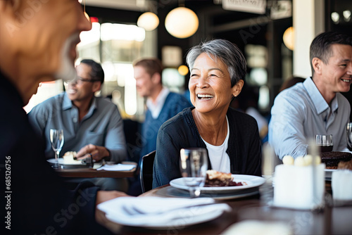 A cheerful group of friends, including seniors and adults, enjoy a happy meal together in a restaurant, sharing laughter and togetherness.