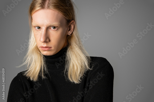 young handsome non binary person in stylish warm black turtleneck looking at camera, fashion photo