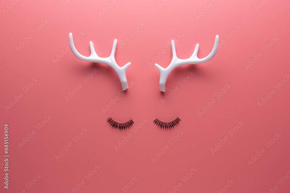 Christmas reindeer face made of eyelashes and white antlers on pink background. Minimal New Year or Christmas concept. Flat lay. Christmas reindeer face made of eyelashes and white antlers on pink background. Minimal New Year or Christmas concept. Flat lay.