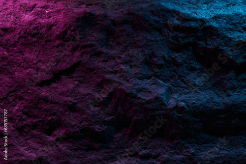 Black stone texture in pink blue neon lighting, dark abstract background. Natural mineral rock close up details, empty backdrop with copy space for design