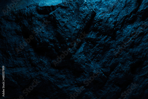 Black stone texture in blue neon lighting, dark abstract background. Natural mineral rock close up details, empty backdrop with copy space for design