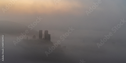Photo Castle perched on a hilltop surrounded by mist at sunrise