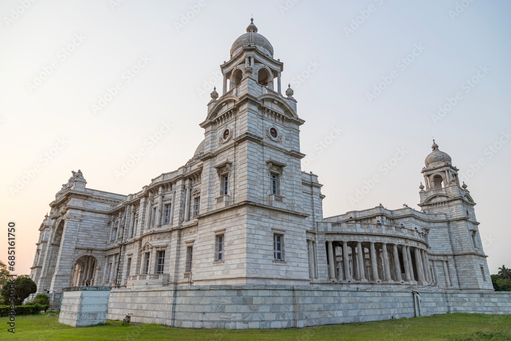 Fototapeta premium View of The famous Victoria Memorial with Garden, a large marble building in Central Kolkata, at the time of Sunrise.