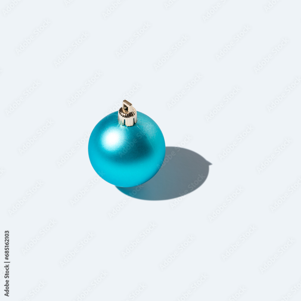 Blue Christmas bauble with strong shadows on white background. Creative Christmas or New Year concept. Blue Christmas bauble with strong shadows on white background. Creative Christmas or New Year concept.