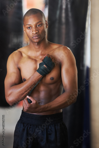 Boxing, gym and black man wrapping hands with fitness, power and training challenge. Strong body, muscle workout and boxer in gym, athlete with confidence and getting ready for fighting competition.