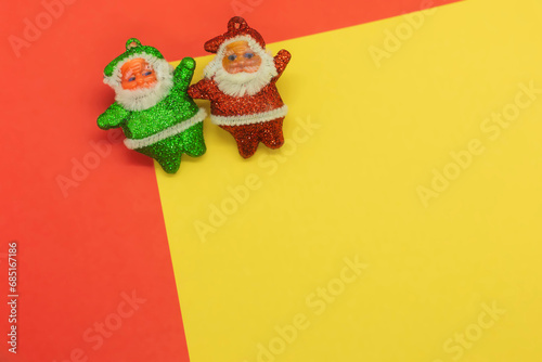 Two Santa Clauses and Christmas Elf on yellow and red background with copy space