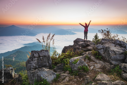 Young woman  in red jacket hiking on the high mountain, Doi Pha Tang, Chiang Rai province, border  of  Thailand and Laos. photo
