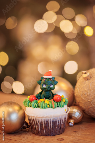 Christmas dragon sweets cupcake on wooden background with gold pine tree with bokeh light  New Year sign for card.