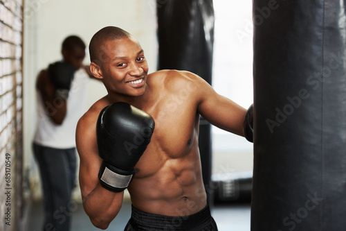 Boxing, gloves and portrait of black man with bag, smile and fitness, power and training challenge. Strong body, muscle and happy boxer in gym, athlete with confidence and pride in competition fight © Marine Gastineau/peopleimages.com