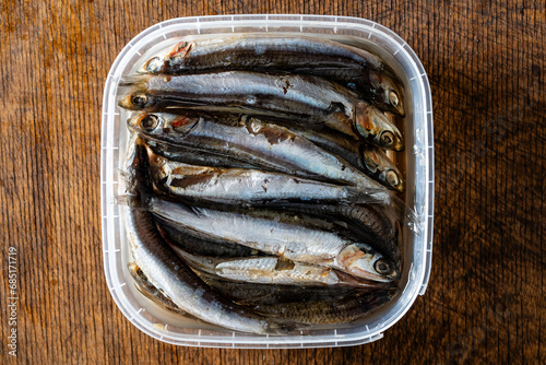 Salted anchovy in oil in a plastic container, closeup, top view. Food background
