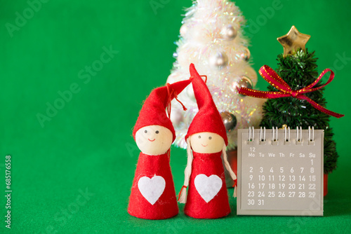 緑の背景にカレンダーとカップル人形のクリスマスイメージ