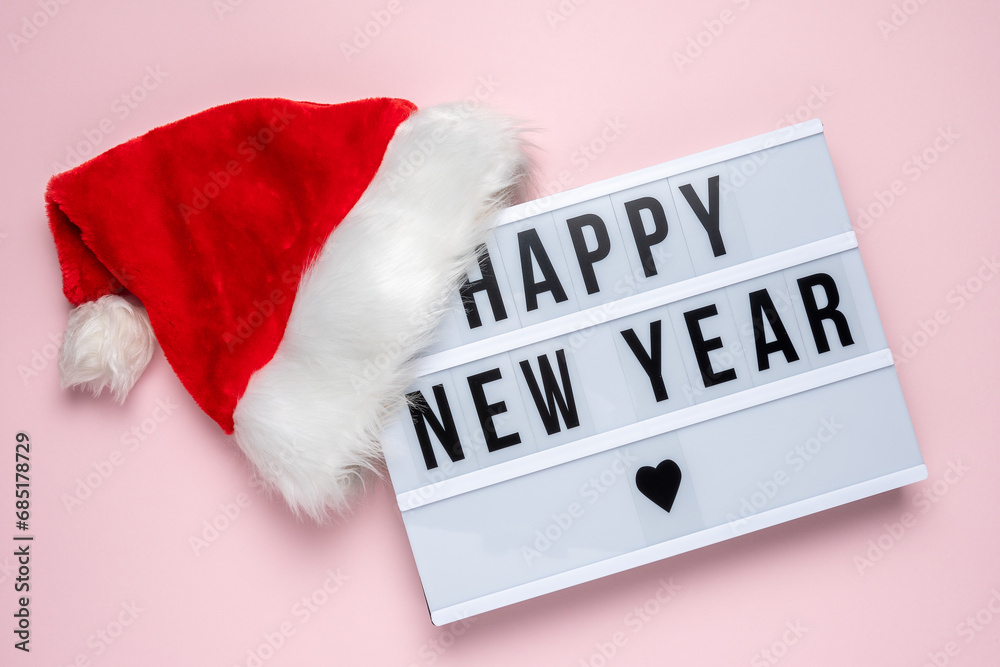 custom made wallpaper toronto digitalLightbox with text HAPPY NEW YEAR and Santa Claus hat on pastel pink background. Minimal Christmas or New Year concept.