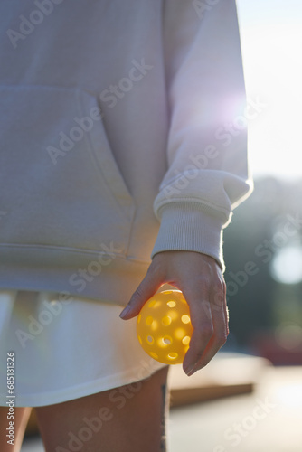 Pickleball player holding a perforated plastic ball in hand photo